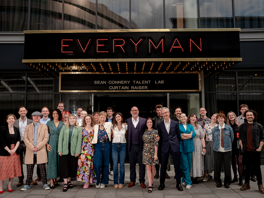 A crowd of people pose for a photograph outside of the Everyman Cinema in London