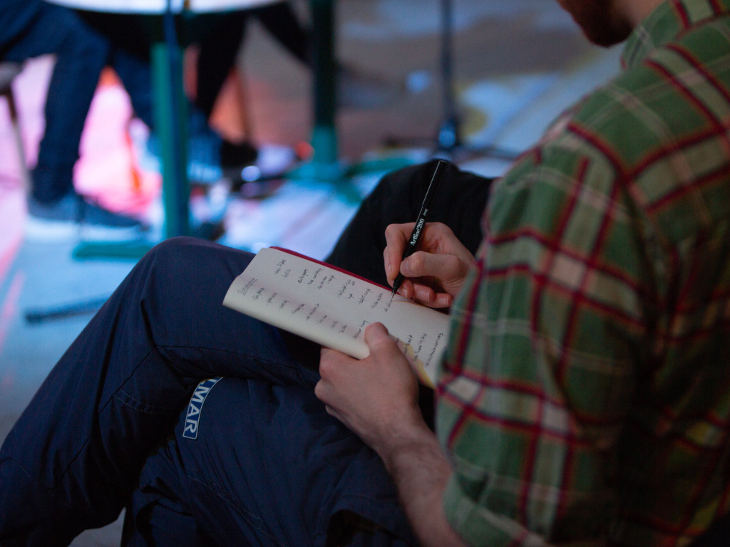 A close-up image of a screenwriter making notes in his notebook on-set