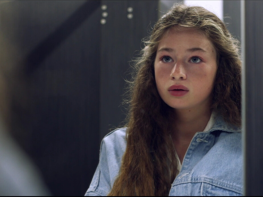 A young girl looks into a mirror, in a still from Heavy by Eve Grant